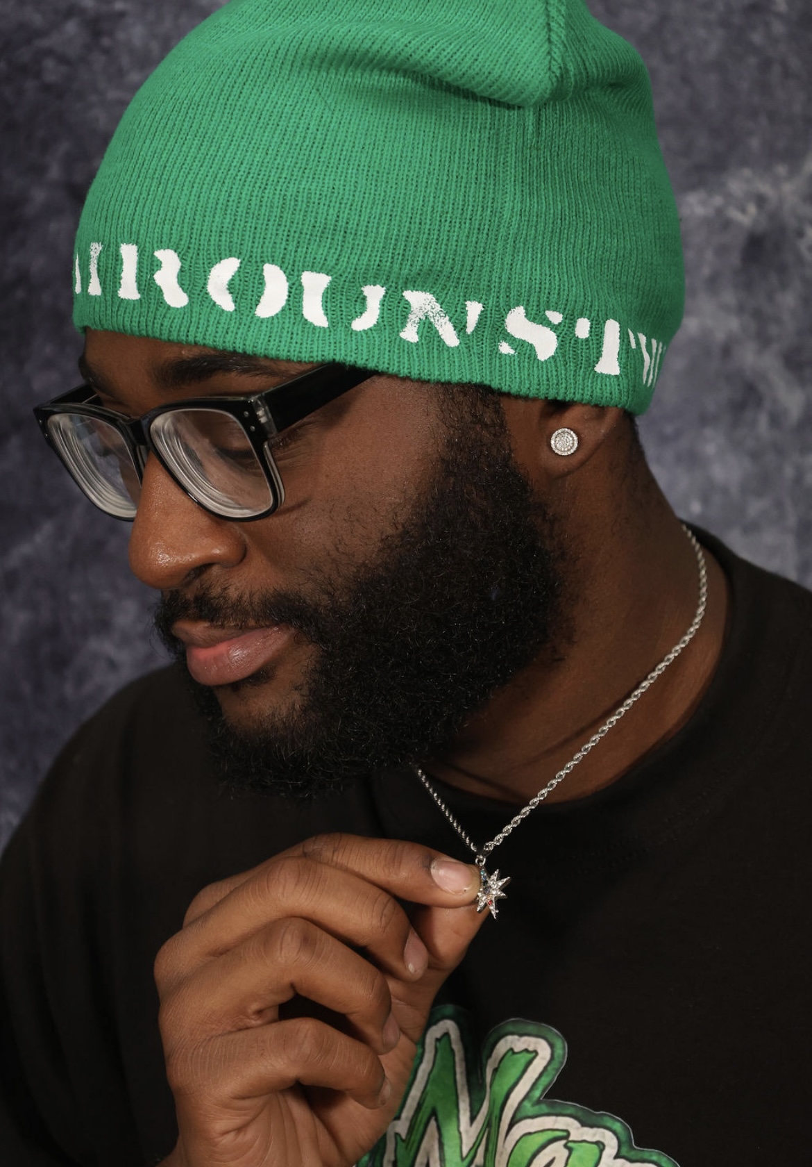 Model wearing a green Hairoun Studios knit cap and eight-point star pendant