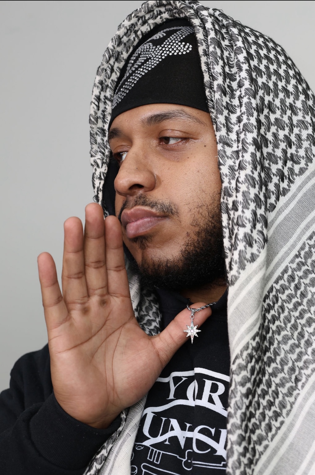 Portrait with a silver eight-point star pendant, crystal knit cap, and patterned drape