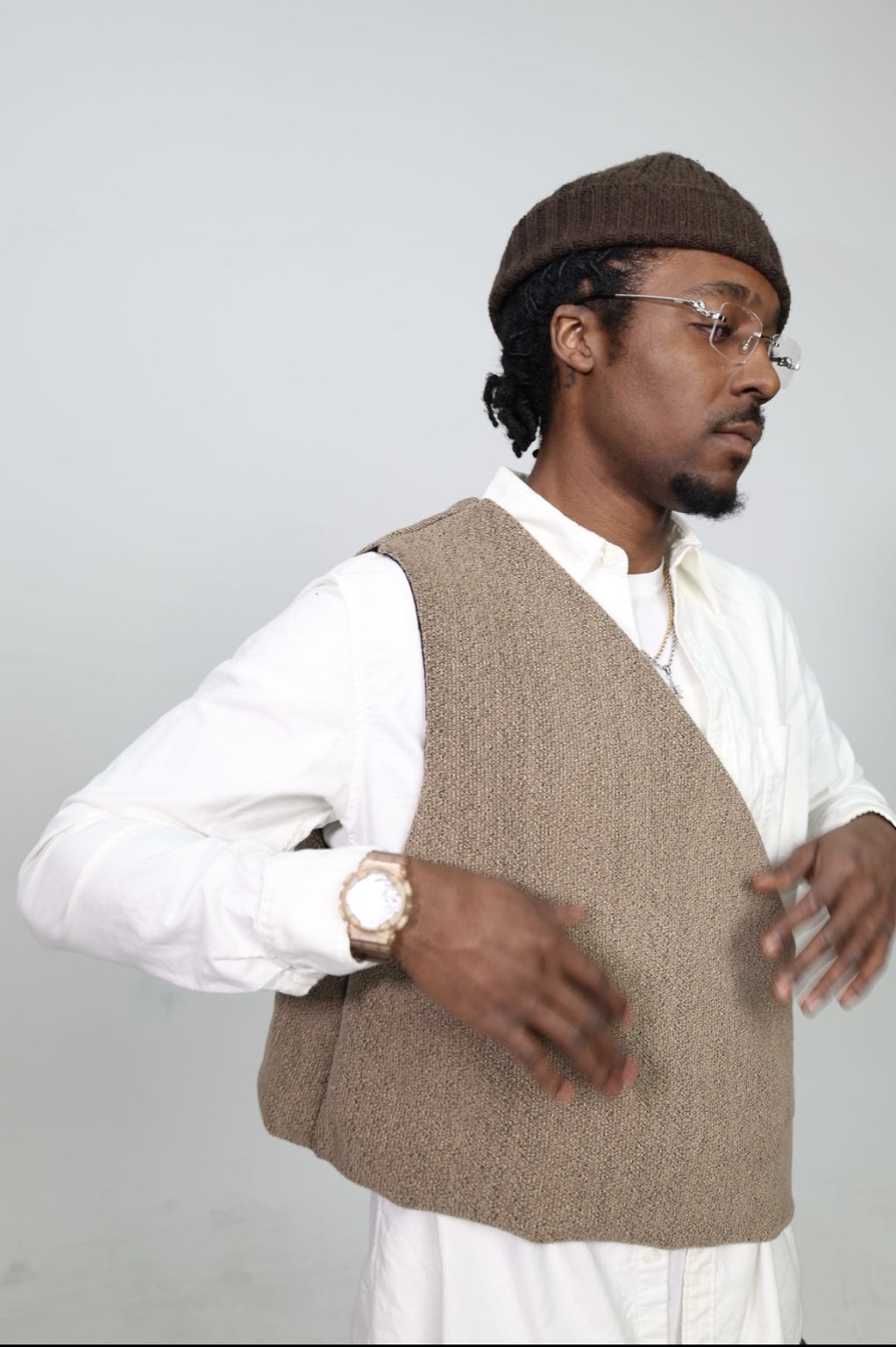Model wearing a sculptural taupe woven vest over a white shirt