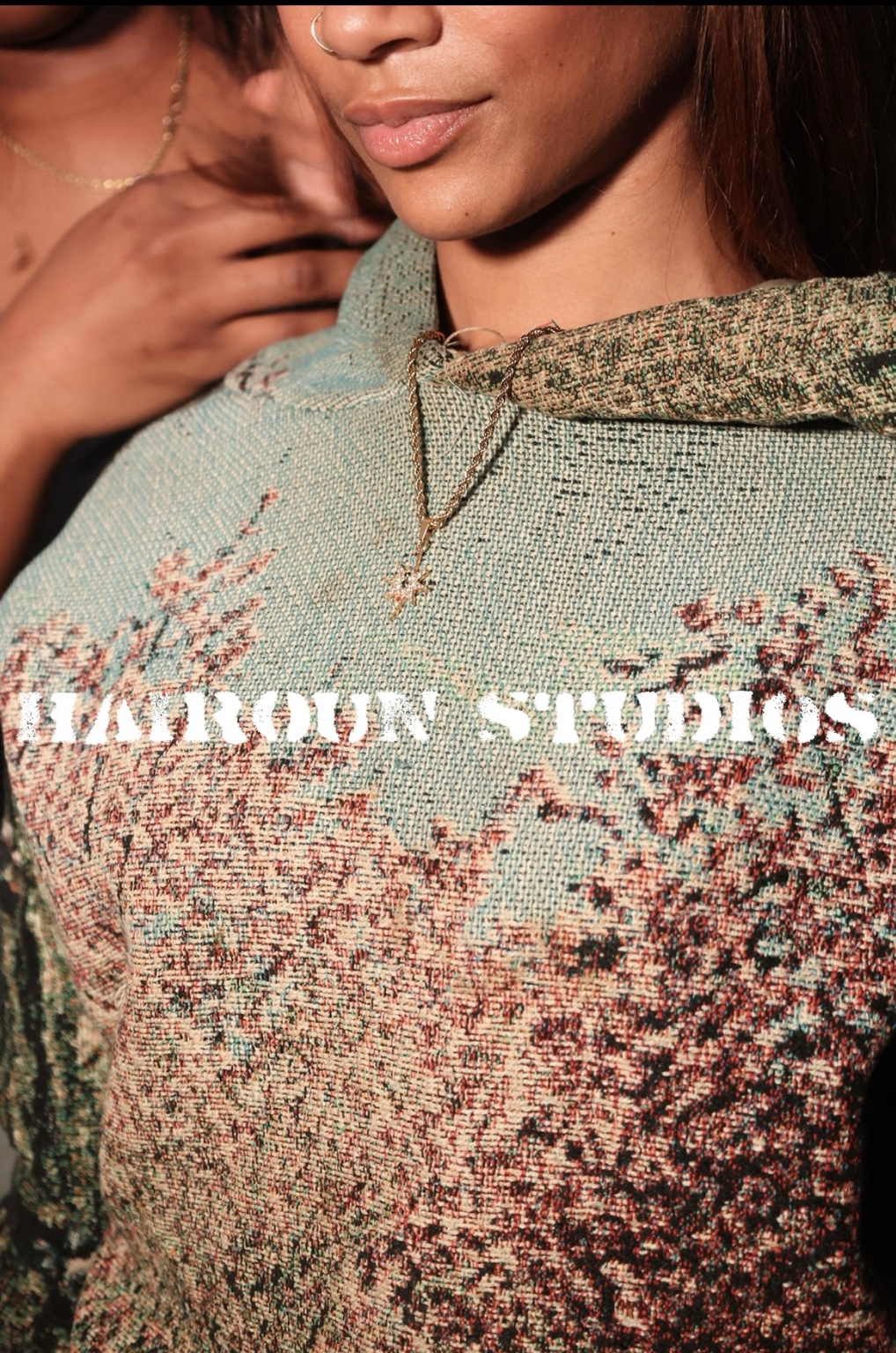 Close detail of a Hairoun Studios woven hooded garment with the gold eight-point star pendant